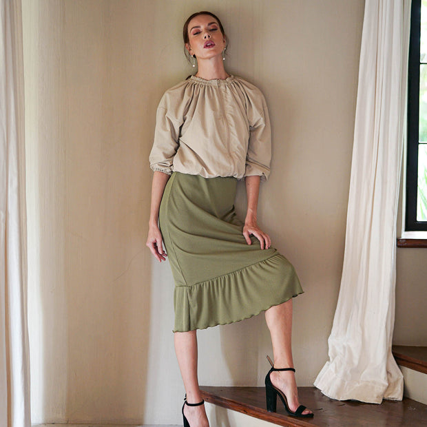 Model wearing Marjorie Ruffle Rib Skirt in Moss Green with a beige blouse and black heels, showcasing a chic and elegant look.