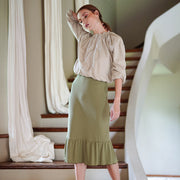 Model wearing Marjorie Ruffle Rib Skirt in moss green with a stylish blouse, showcasing a sophisticated look.