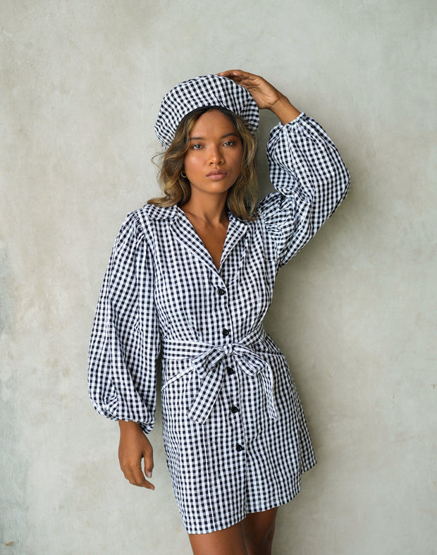 Model wearing Meghan mini gingham dress in black with puff sleeves and bow detail, styled with matching hat.